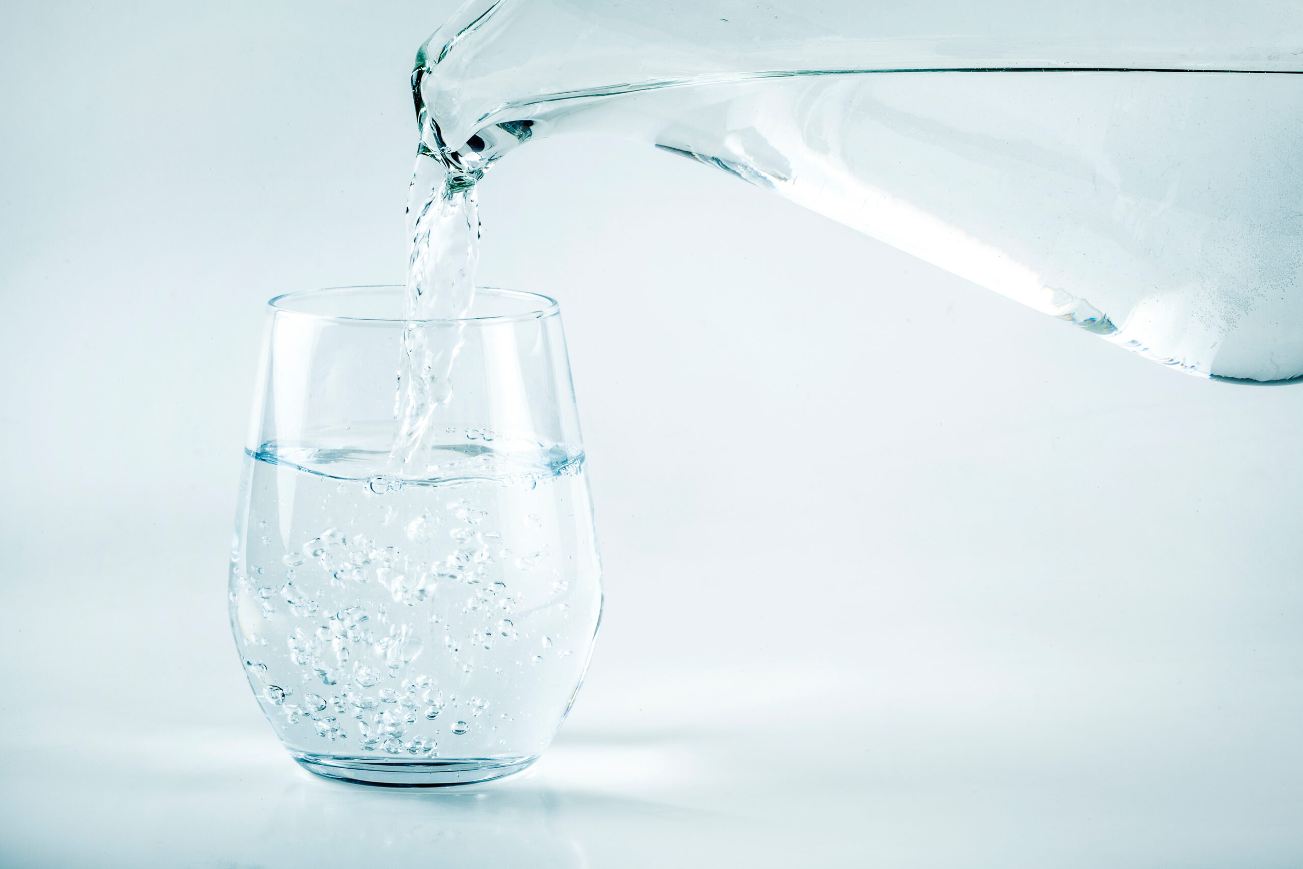 Water being poured from a bottle into a glass of water.